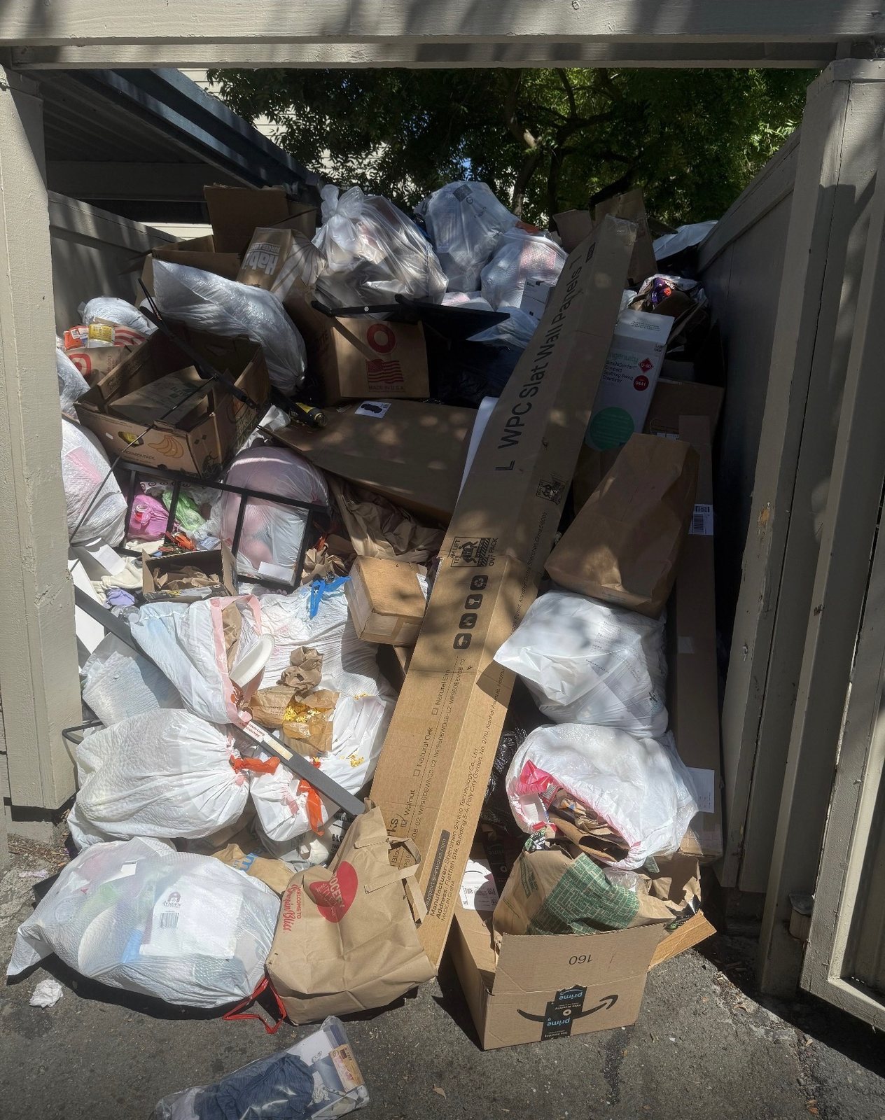 Services Apartment dumpster enclosure overflowing with bags and boxes before a property cleanout in Elk Grove, CA